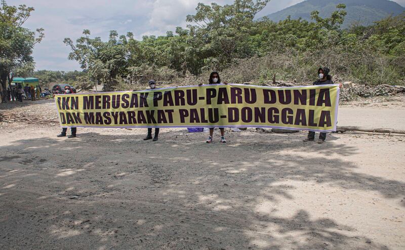 Empat warga yang tergabung dalam Koalisi Petisi Palu-Donggala membentangkan spanduk bertuliskan IKN merusak paru-paru dunia dan masyarakat Palu-Donggala saat menggelar aksi unjuk rasa di lingkar tambang galian C Kelurahan Buluri, Palu, Sulawesi Tengah, 21 Mei 2024. [Taufan Bustan/BenarNews)