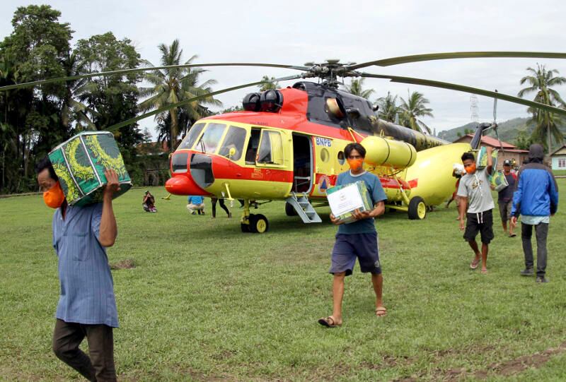 Warga korban gempa membantu mengangkat bantuan logistik yang dikeluarkan dari sebuah helikopter di Majene, Sulawesi Barat, 20 Januari 2021. [AP]
