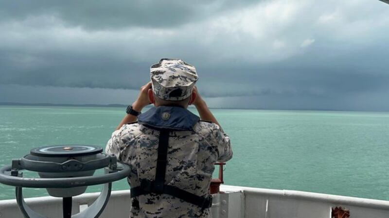 Petugas Badan Penegak Maritim Malaysia, menggunakan teropong, berupaya mencari korban kapal yang tenggelam di perairan Tanjung Balau, Johor, 17 Desember 2021. [Dok. Badan Penegakan Maritim Malaysia]