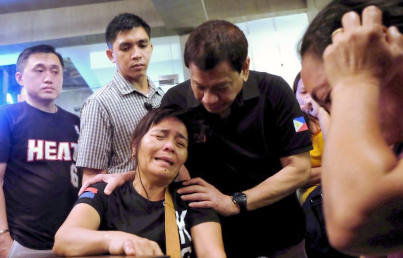 Philippine President Rodrigo Duterte comforts a relative of one of the victims of a fire that engulfed a shopping mall in Davao City, Dec. 23, 2017.