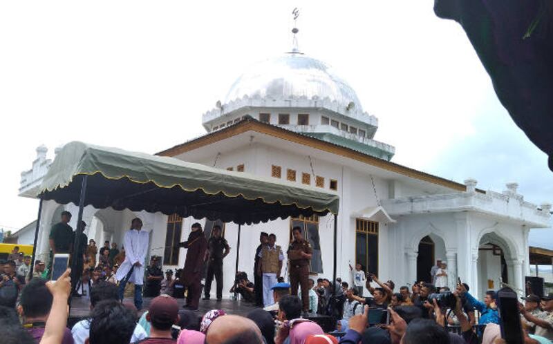 Warga mengabadikan prosesi eksekusi cambuk di halaman Masjid Babussalam di Banda Aceh, 27 Februari 2018. (Nurdin Hasan/BeritaBenar)