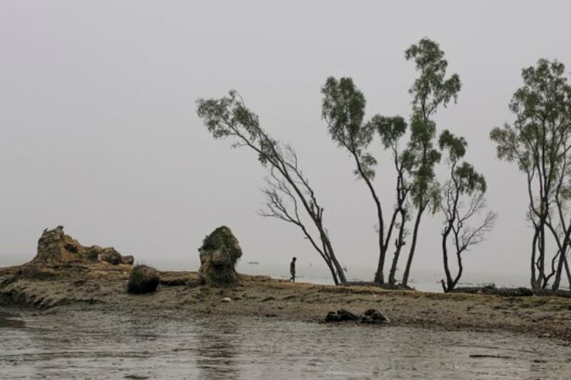 Seorang pria berjalan melewati hamparan tanah di mana rumahnya pernah berdiri di Bhola, sebuah pulau di Bangladesh di mana Sungai Meghna mengalir ke Teluk Benggala, 17 November 2015. [AP]