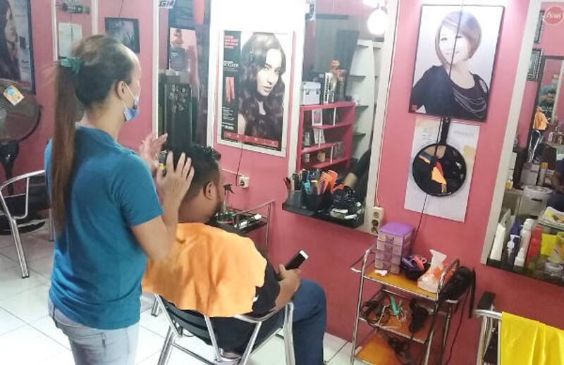 Seorang waria memijat kepala pelanggannya setelah dipangkas rambut di Banda Aceh, 3 Februari 2018. (Nurdin Hasan/BeritaBenar) 