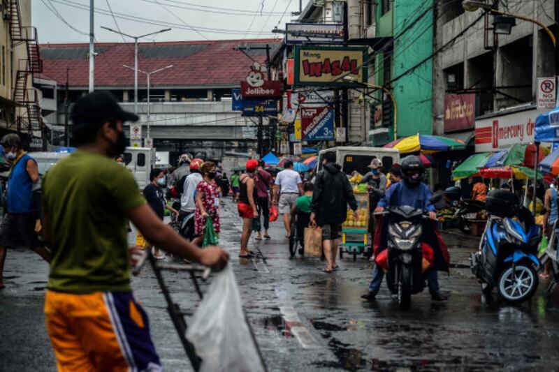 Market goers fill a rain-soaked street at the Blumentritt Markey in Manila, May 15, 2020. [Jojo Rinoza/BenarNews]