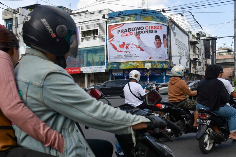 Pengendara melewati baliho bergambar Prabowo Subianto, Ketua Umum Partai Gerindra, salah satu bakal calon presiden dalam pemilu tahun depan, didampingi foto Gibran Rakabuming Raka, putra sulung Presiden Joko "Jokowi" Widodo yang juga Wali Kota Surakarta dengan teks bertuliskan "Prabowo Gibran untuk Indonesia", di Medan, Sumatra Utara, 15 Oktober 2023. [Antara Foto/Fransisco Carolio/via Reuters]