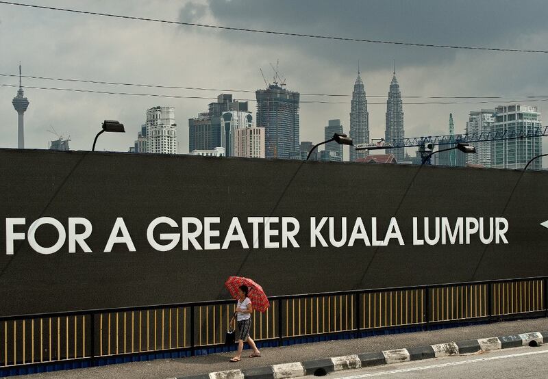 A woman walks past the construction site of the 1Malaysia Development Berhad (1MDB) flagship Tun Razak Exchange in Kuala Lumpur, July 3, 2015.