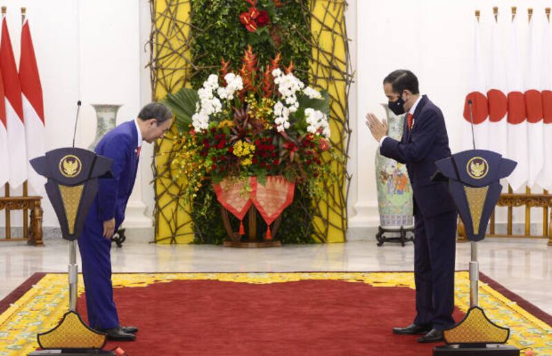 Japanese Prime Minister Yoshihide Suga (L) greets Indonesian President Joko Widodo during a joint press conference at the presidential palace in Bogor, on the outskirts of Jakarta, Oct. 20, 2020.