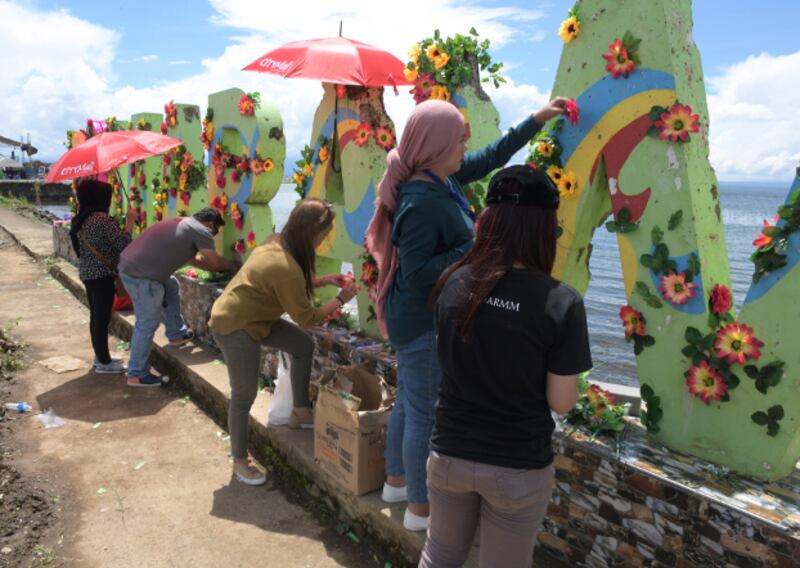 Members of an events-organizing group use flowers to decorate the bullet-riddled iconic sign “I love Marawi” to mark the second anniversary of the city's liberation, Oct. 17, 2019. (Froilan Gallardo/BenarNews)