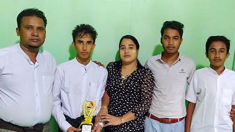 Rohingya student Muhammad Ayaz (second from left) holds a trophy he received in recognition of his scholastic achievements as he stands beside his parents and brothers at their home in Buthidaung town, in Myanmar's Rakhine state, in an undated photo. [Photo courtesy of Muhammad Ayaz's family]