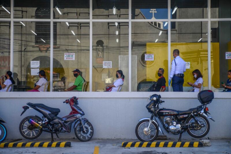 A security guard wearing a face mask monitors social distancing protocols of people waiting to enter a department store in Dagupan City, northern Philippines, May 18, 2020. [Jojo Rinoza/BenarNews]