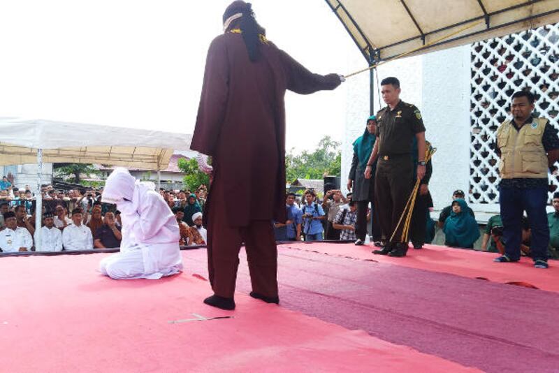 Novia Sri Wahyuni menutup wajahnya ketika dicambuk algojo di Banda Aceh, 19 Januari 2018. (Nurdin Hasan/BeritaBenar)