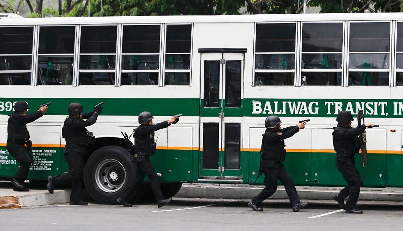 Police aim their pistols toward a bus during a hostage-taking scenario as part of anti-terrorism drills conducted by police and military units in Manila, April 12, 2018. 