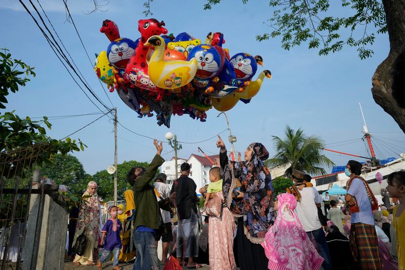 Seorang ibu membeli balon untuk anaknya setelah salat Idul Fitri di pelabuhan Sunda Kelapa di Jakarta, 2 Mei 2022. [AP]