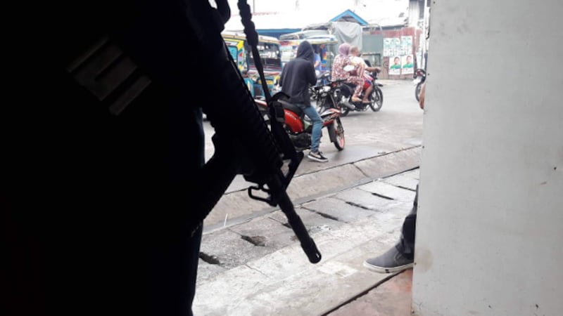 A soldier armed with an assault rifle guards a busy street in the southern Philippine town of Jolo, April 10, 2019. [Mark Navales/BenarNews]