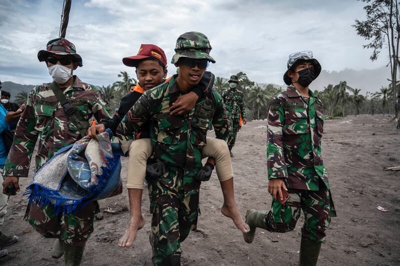Tim penyelamat membantu evakuasi warga di desa Sumberwuluh, Lumajang, Jawa Timur pada 6 Desember 2021. [AFP]