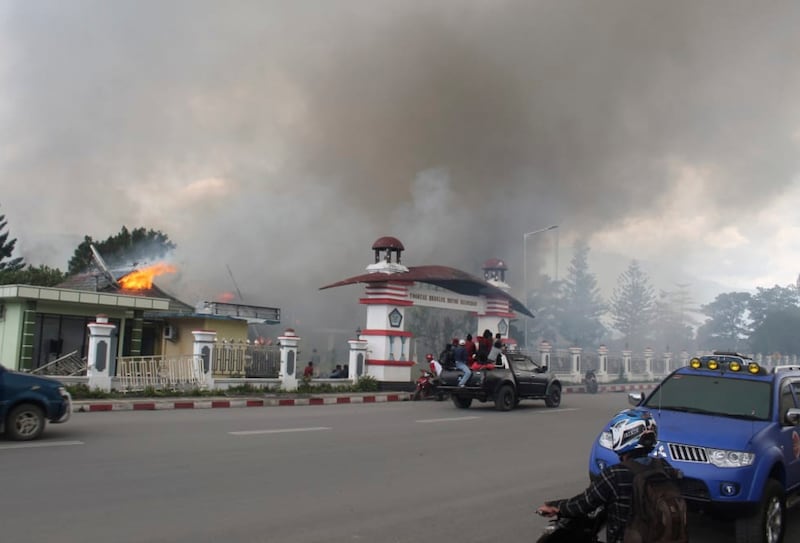 Residents drive past a burning government building during a protest that turned violent in Wamena, Papua province, Indonesia, Sept. 23, 2019. [AP]