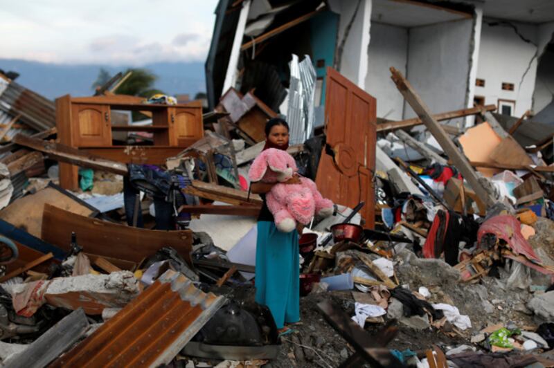 A woman holds a stuffed rabbit after it was found at her destroyed home, where she said she had lost her three children in earthquakes and a tsunami that battered Palu, in Indonesia's Central Sulawesi province, Oct. 7, 2018.