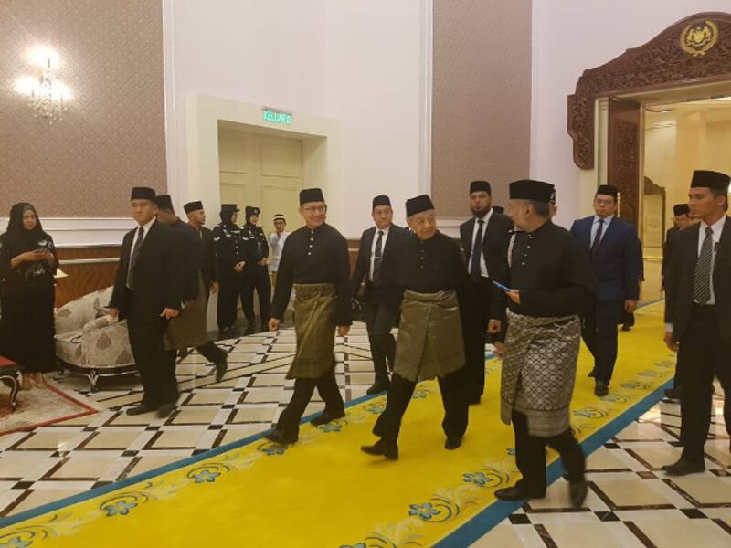 Pakatan Harapan Chairman Mahathir Mohamad (third from right) talks to his son Mokhzani while walking to a ceremonial hall at the royal palace for his swearing-in ceremony as Malaysia's new prime minister, May 10, 2018. [S. Mahfuz/BenarNews]