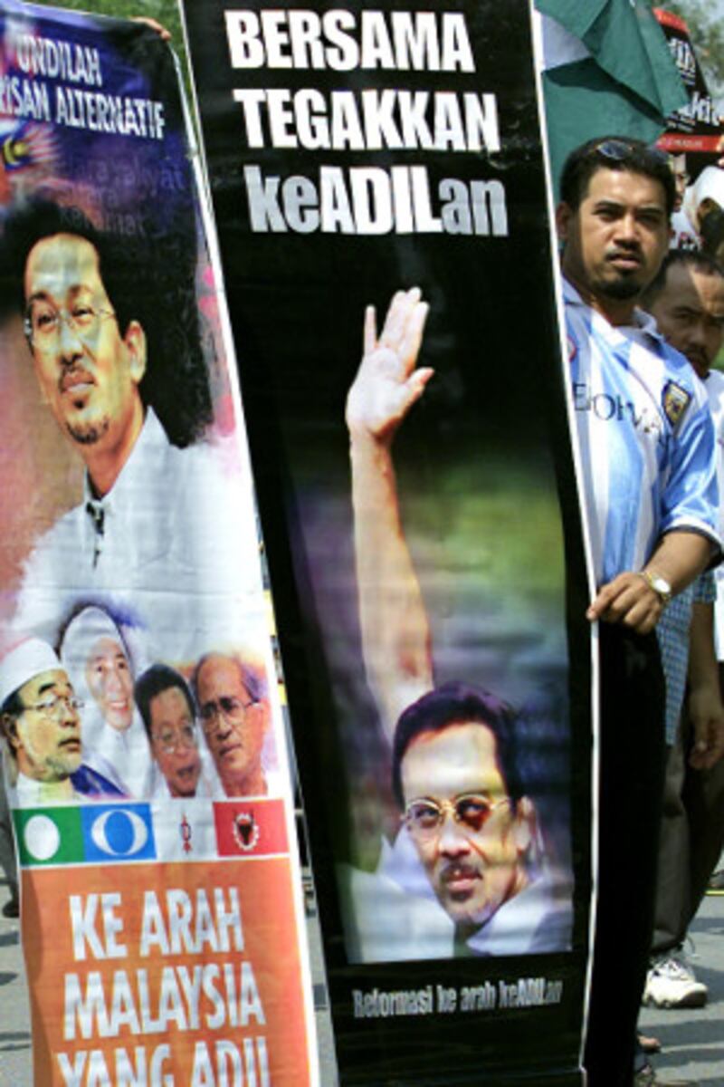 A supporter of Anwar Ibrahim holds a banner depicting Anwar's black eye during a peaceful demonstration to mark the opposition leader's 54th birthday, in Sungai Buloh, Malaysia, Aug. 12, 2001. [AFP]