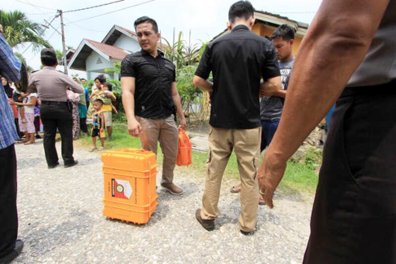 Polisi membawa barang bukti yang telah dimasukkan dalam kotak dari lokasi penggeledahan rumah terduga teroris di Kabupaten Kampar, Riau, 24 Oktober 2017. (Dina Febriastuti/BeritaBenar) 