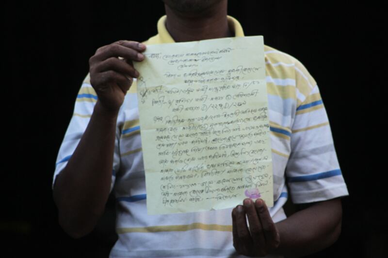 Mohammad Rashid, an official with the development committee at the Leda refugee camp in Teknaf, Bangladesh, holds up a letter from Sakhina Khatun, a mother of two missing Rohingya girls seeking the committee's help in finding them, Aug. 26, 2018. (Sharif Khiam/BenarNews)