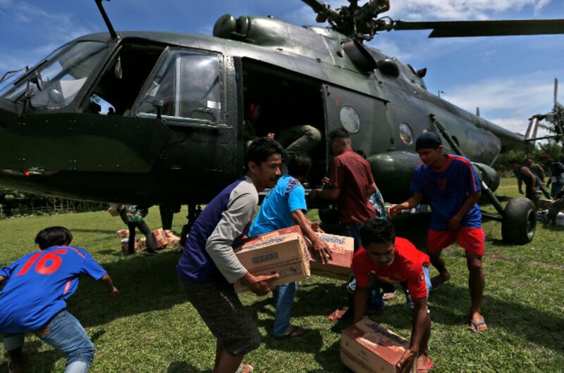 Earthquake survivors carry relief goods delivered by an Indonesian Army helicopter in Poroo, Central Sulawesi, Oct. 7, 2018. [AP]