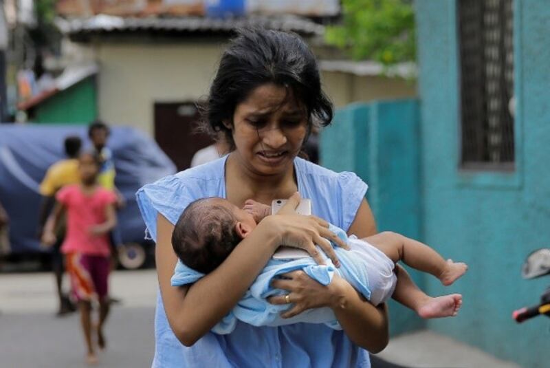 A Sri Lankan woman living near St. Anthony's Shrine church runs for safety with her infant after police found explosive devices in a parked vehicle in Colombo, Sri Lanka, April 22, 2019, a day after nearly 300 people were killed in Easter Sunday bombings that targeted churches and luxury hotels in the country. [AP]