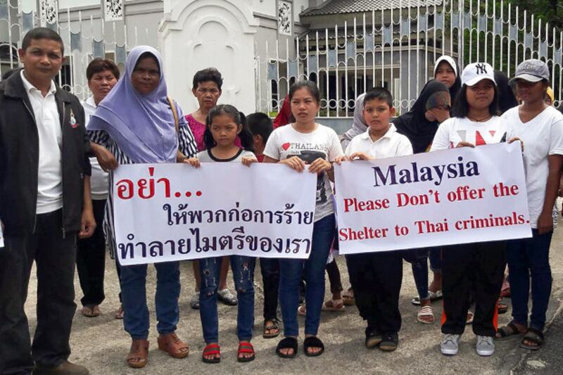 Members of an activist group, “Deep South Peaceful Thais,” hold signs outside the Malaysian Consular office in southern Thailand's Songkhla province, urging Malaysia to stop supporting insurgents, Oct. 24, 2018. (Mariyam Ahmad/BenarNews)