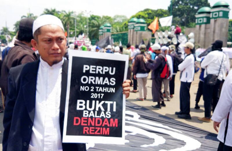 Seorang demonstran membawa poster penolakan terhadap Perppu Ormas dalam unjuk rasa di depan Gedung DPR di Jakarta, 24 Oktober 2017.