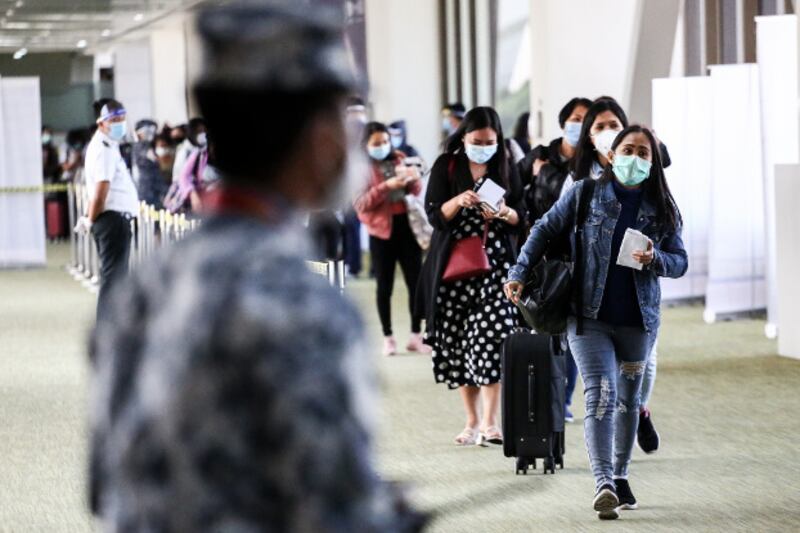 Filipino contract workers wearing protective masks arrive on a flight from Hong Kong at Ninoy Aquino International Airport in Manila, May 13, 2020. [Basilio Sepe/BenarNews]