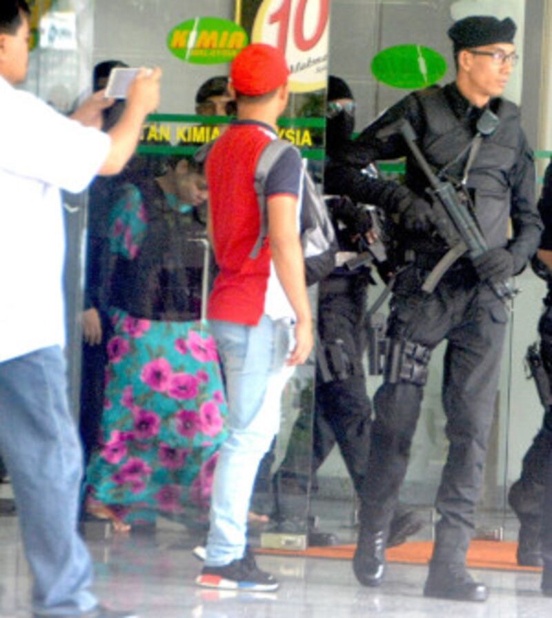 Police escort Indonesian Siti Aisyah (wearing flowery dress) from the Malaysia's Chemistry Department complex near Kuala Lumpur, Oct. 9, 2017. [Fadzil Aziz/BenarNews]
